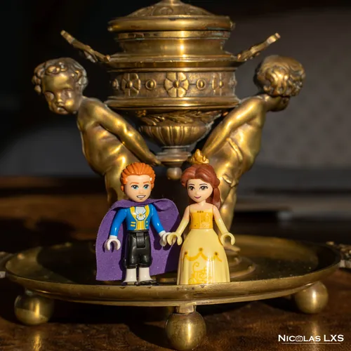 Figurines LEGO de la Belle et du prince devant un objet en laiton