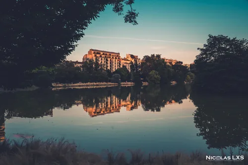 Lac du parc Montsouris reflétant un immeuble au coucher du soleil